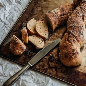 "Freshly baked whole-grain brown bread on a wooden tray with a knife, highlighting its wholesome texture and natural appeal."